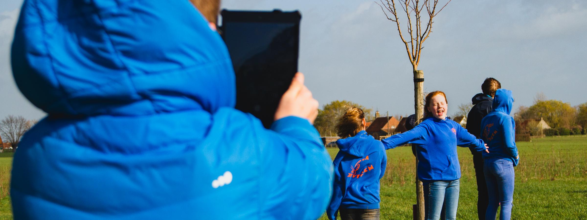 Jongen neemt met een tablet een foto van anderen