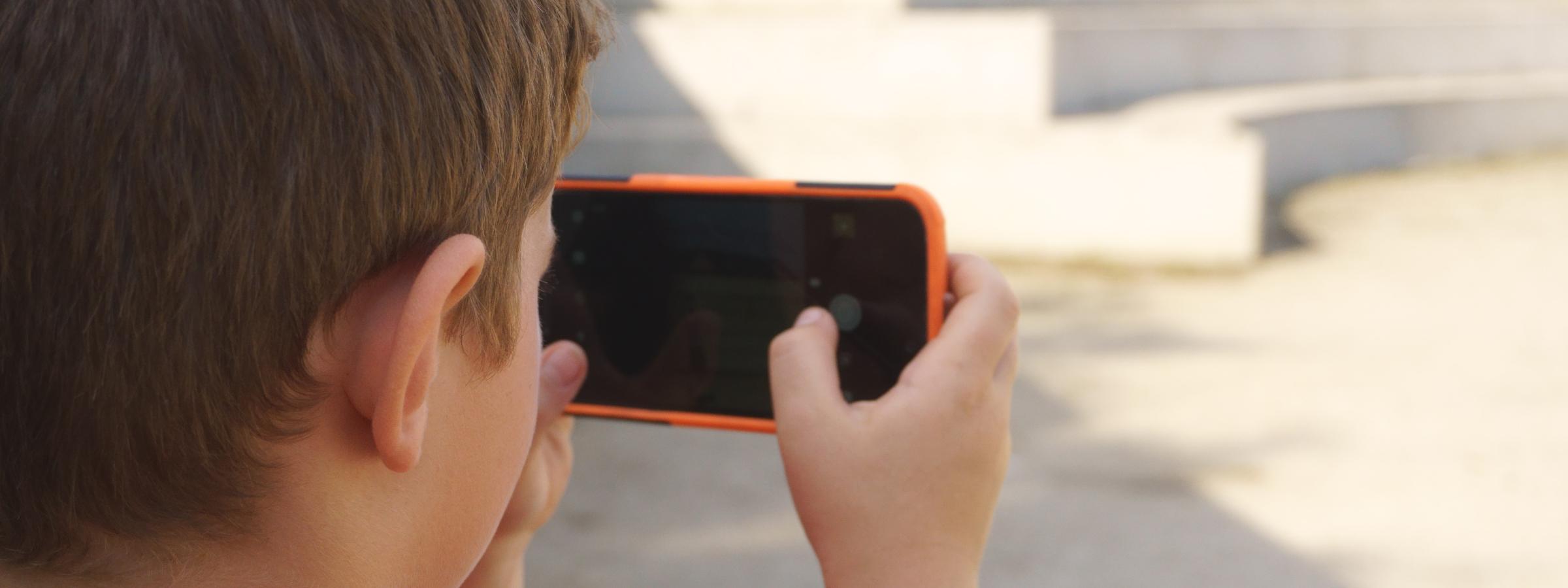 Jongen filmt horizontaal met smartphone 