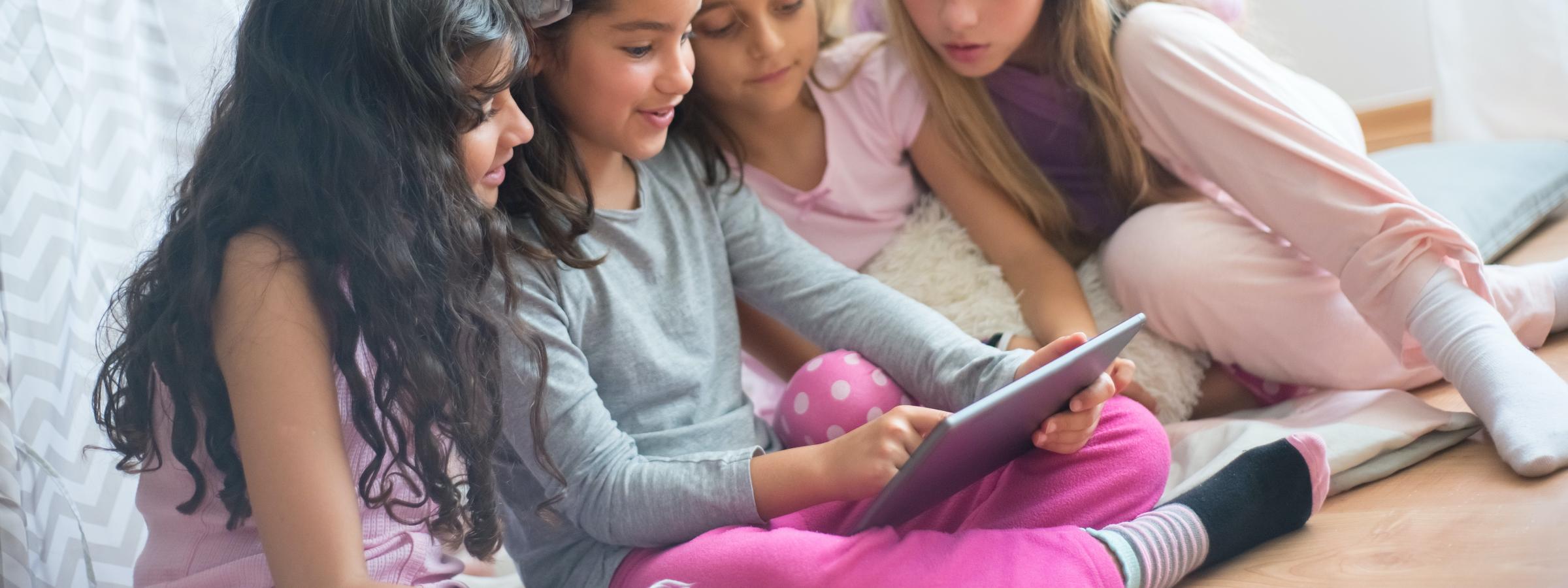 Vier meisjes in een woonkamer met een tablet