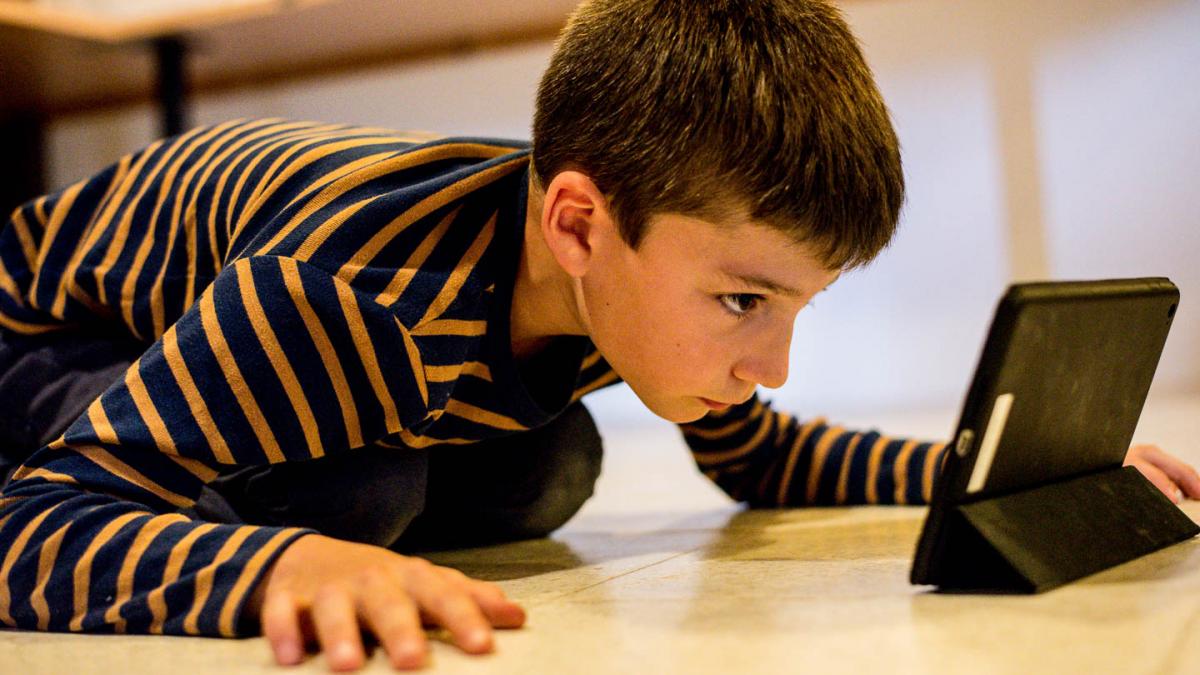 Jongen kijkt geconcentreerd naar tablet