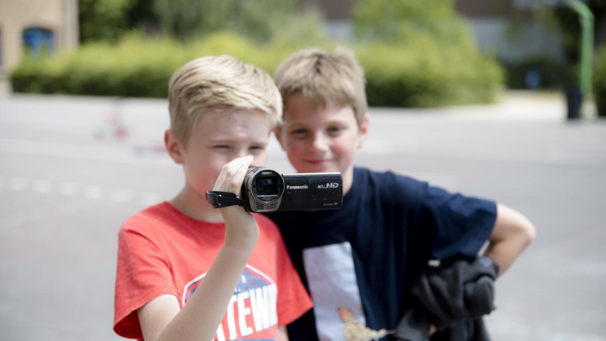 Jongen met camera vast, jongen achter hem kijkt mee wat hij filmt