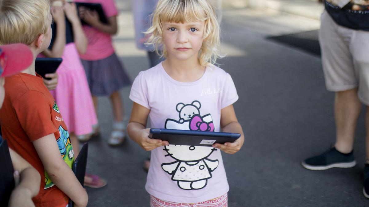 Meisje, kleuter met tablet, omringd door andere kleuters met tablets