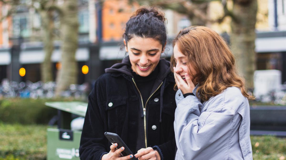 Meisje toont iets op haar smartphone aan ander meisje, ze lachen